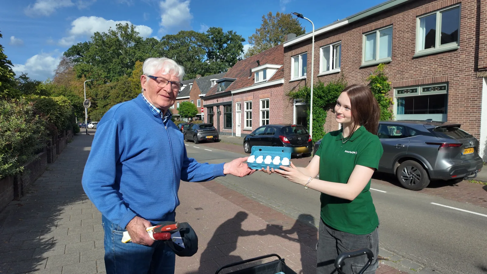 Een Buurtbaas overhandigt een doos verse eieren aan een klant in de buurt